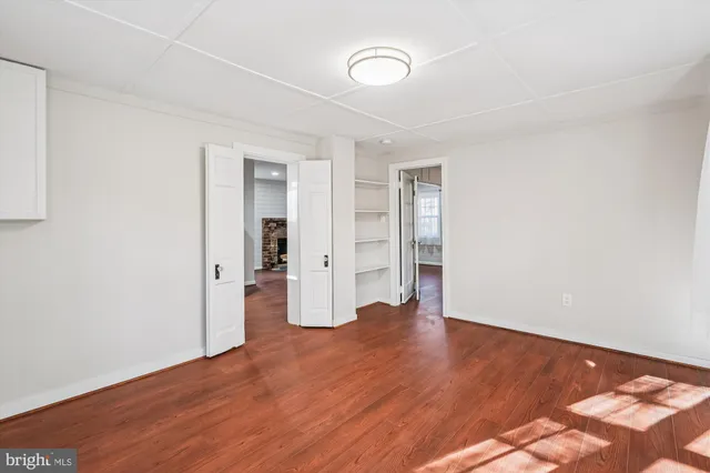 a view of an empty room with wooden floor and closet