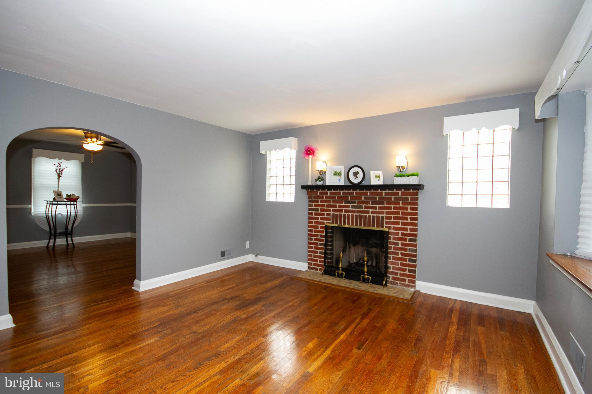2022 Crestview Road Baltimore, MD 21239 - Photo 2 of 14 an empty room with wooden floor fireplace and windows