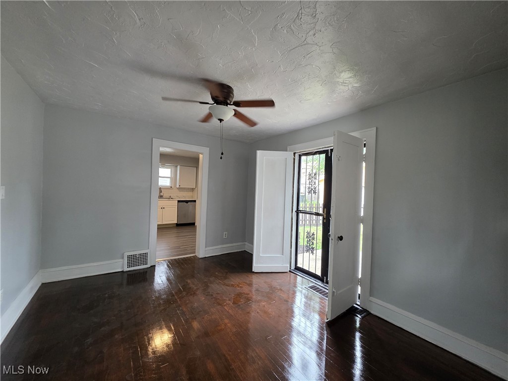 991 Helmsdale Road Cleveland, OH 44112 - Photo 6 of 39 Unfurnished room with hardwood / wood-style flooring, ceiling fan, and a textured ceiling