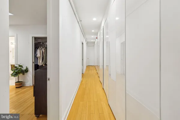 a view of a hallway with wooden floor and a bathroom