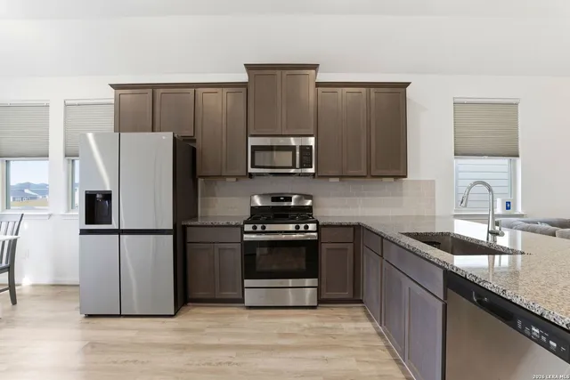 a kitchen with granite countertop wooden cabinets a refrigerator and a stove top oven