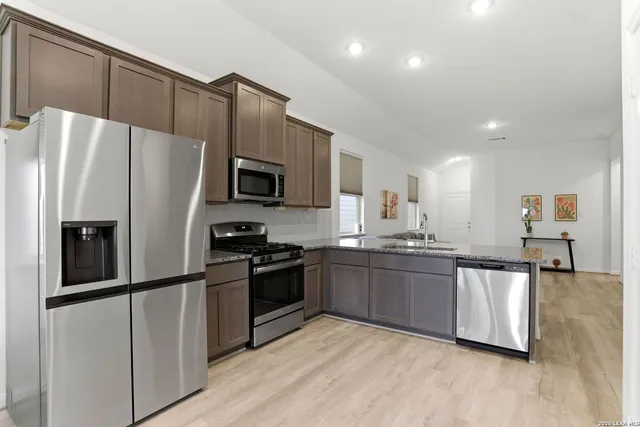 a kitchen with granite countertop a refrigerator and a stove top oven