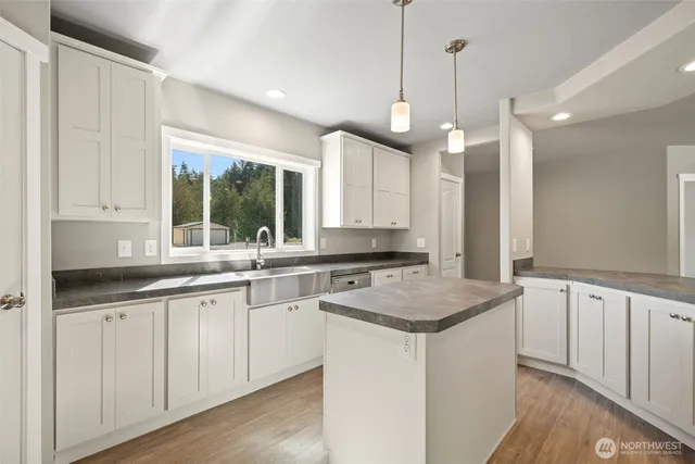 a kitchen with granite countertop a sink a counter space appliances and a window