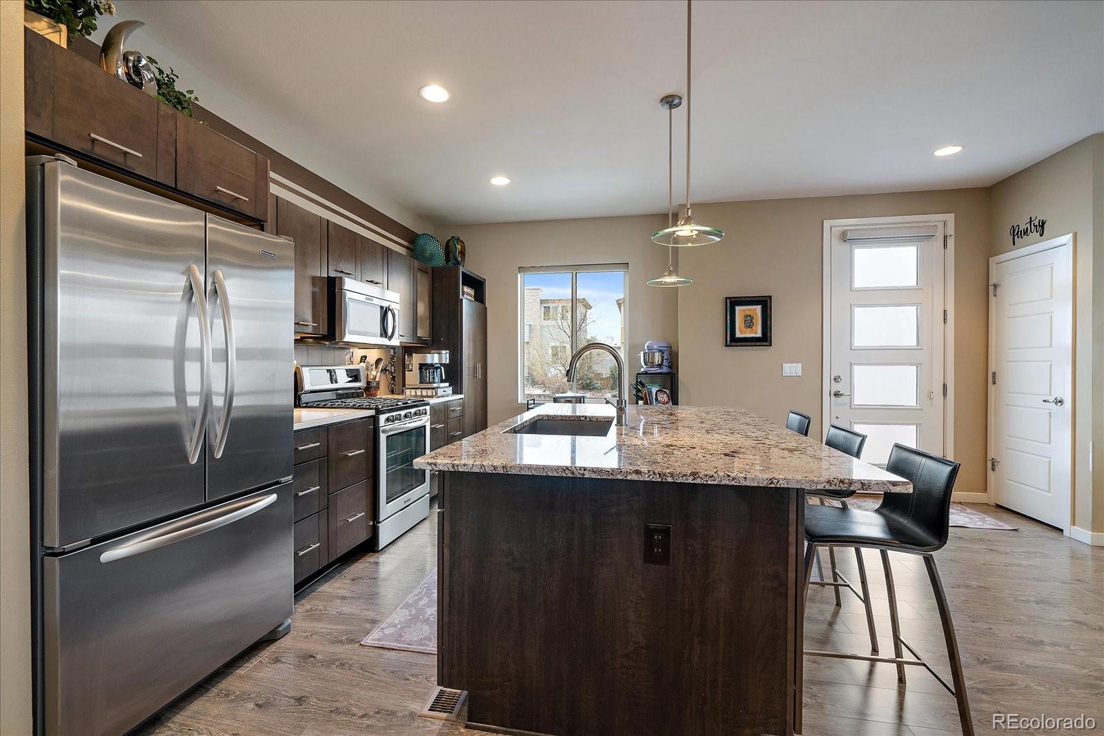 9717 Dunning Circle Highlands Ranch, CO 80126 - Photo 12 of 38 a kitchen with kitchen island a counter top space a sink stainless steel appliances and cabinets