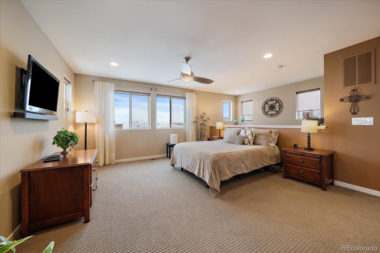 9717 Dunning Circle Highlands Ranch, CO 80126 - Photo 23 of 38 a spacious bedroom with a bed and a flat screen television
