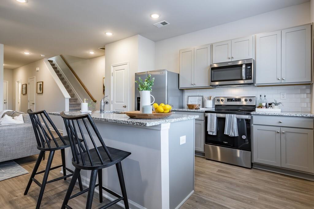 513 Kirkland Road, Unit CARRAWAY Covington, GA 30016 - Photo 9 of 53 a kitchen with stainless steel appliances granite countertop a stove a sink dishwasher a microwave oven with granite countertops and cabinets