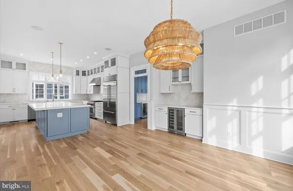 a large kitchen with stainless steel appliances a large counter top a stove and a wooden floors