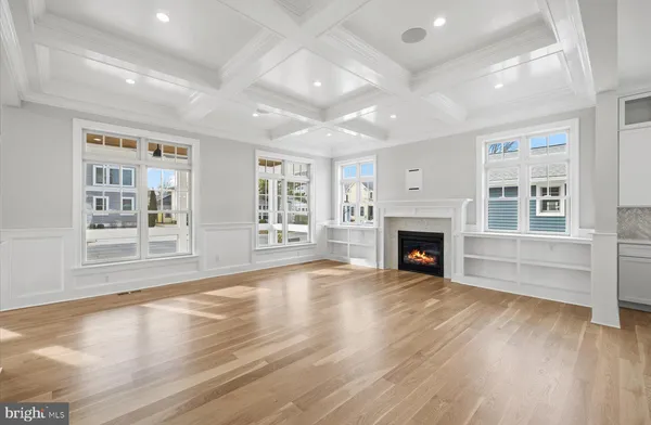 an empty room with windows a fireplace and wooden floor