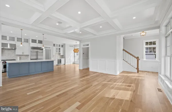 a view of an empty room with kitchen and window
