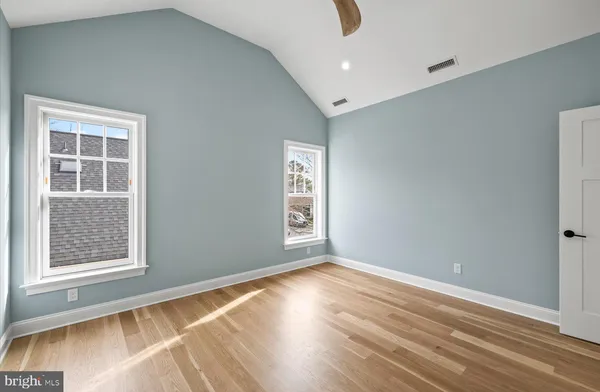 an empty room with wooden floor and windows
