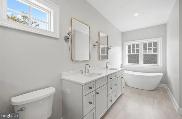 a bathroom with a granite countertop toilet a sink a mirror and a window