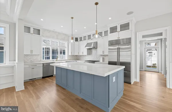 a kitchen with stainless steel appliances granite countertop a kitchen island a stove a refrigerator a sink and a wooden floors