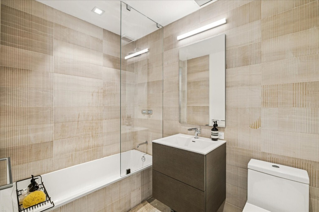 75 1st Avenue, Unit 4B Manhattan, NY 10003 - Photo 4 of 6 a bathroom with a tub sink toilet and mirror