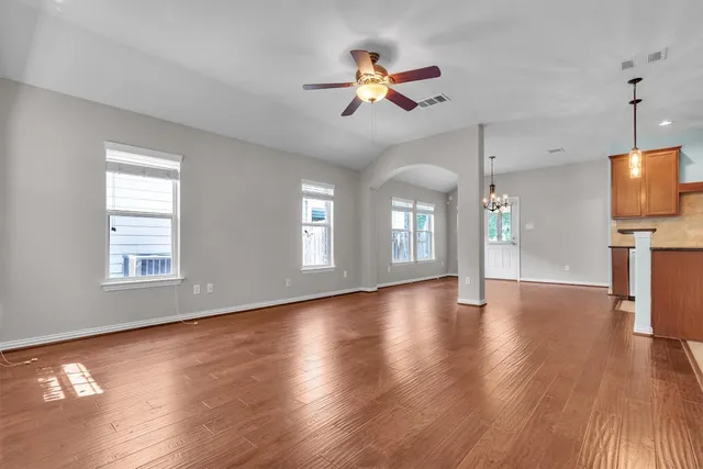 a view of empty room with wooden floor and fan