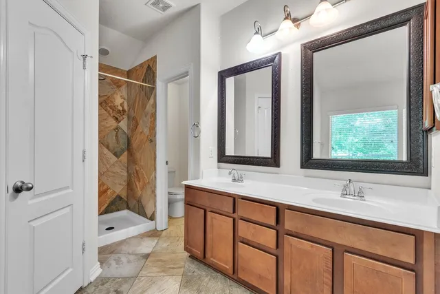 a bathroom with a double vanity sink mirror and shower