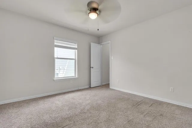 an empty room with a window and a ceiling fan