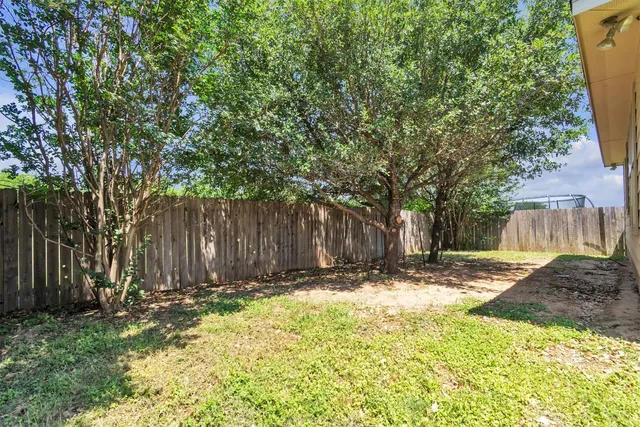 a view of a backyard with large trees and wooden fence