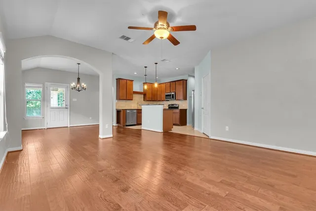 a view of a kitchen with a sink a kitchen a refrigerator a ceiling fan and wooden floor