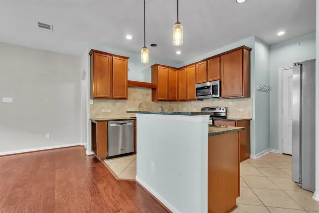 a kitchen with stainless steel appliances granite countertop a refrigerator a stove top oven a sink and dishwasher
