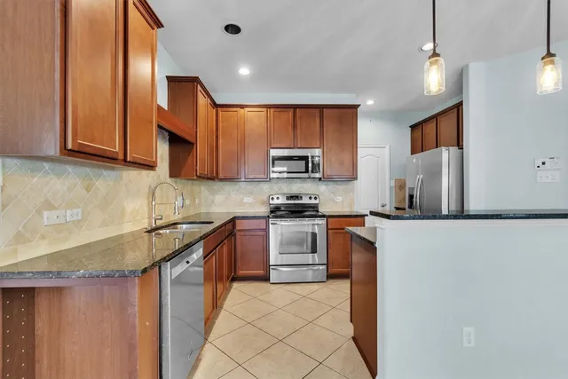 a kitchen with stainless steel appliances granite countertop a refrigerator a stove top oven a sink and dishwasher