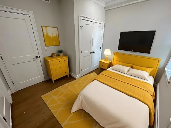 a bedroom with a bed and a flat tv screen on the dresser