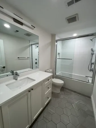 a bathroom with a granite countertop sink toilet and shower
