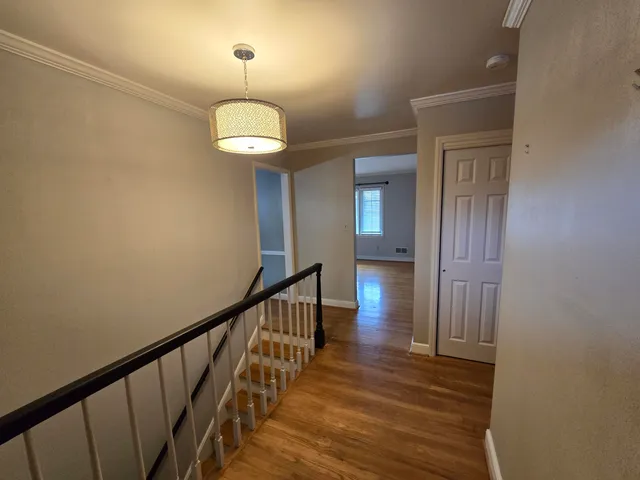 a view of a hallway with wooden floor and staircase