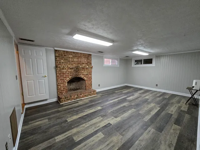 a view of empty room with fireplace and wooden floor