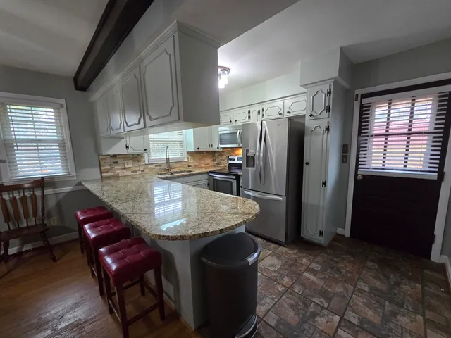 a kitchen with stainless steel appliances granite countertop a sink refrigerator and cabinets