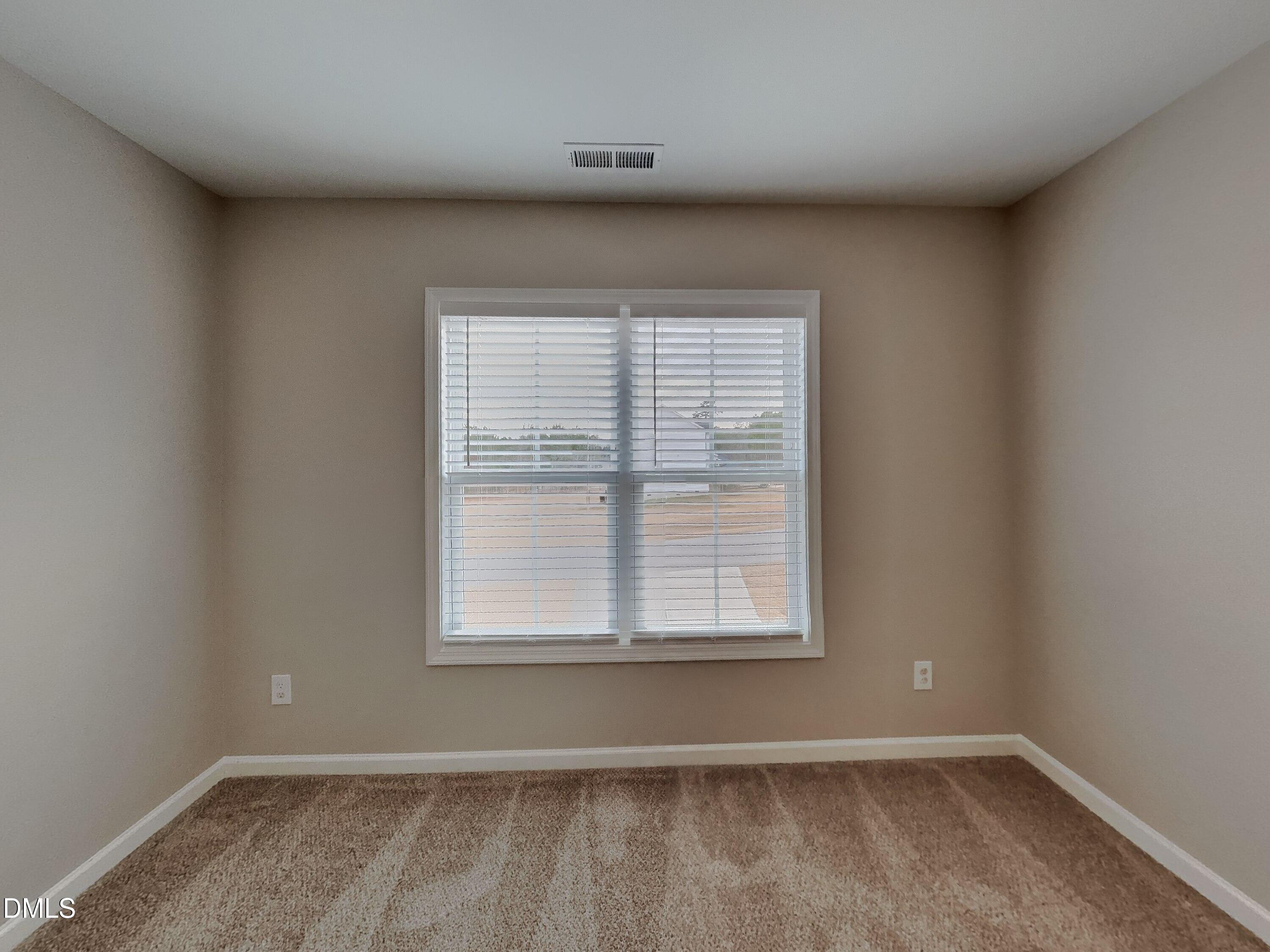 803 Springtooth Drive Zebulon, NC 27597 - Photo 11 of 16 an empty room with wooden floor and windows