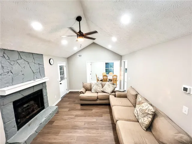 a living room with furniture a fireplace and a ceiling fan