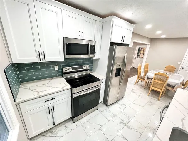 a kitchen with white cabinets and stainless steel appliances