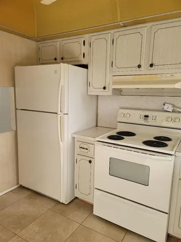 a white refrigerator freezer and a stove sitting inside of a kitchen