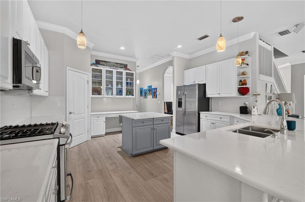 9970 Rookery Circle Estero, FL 33928 - Photo 13 of 50 Gourmet kitchen featuring white cabinetry, light countertops, a central island, stainless steel appliances, and wood-finish flooring