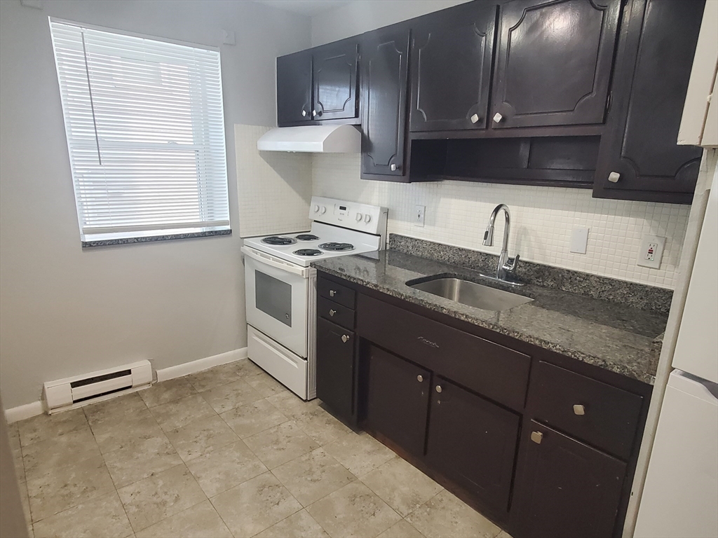a kitchen with granite countertop a sink stove and cabinets