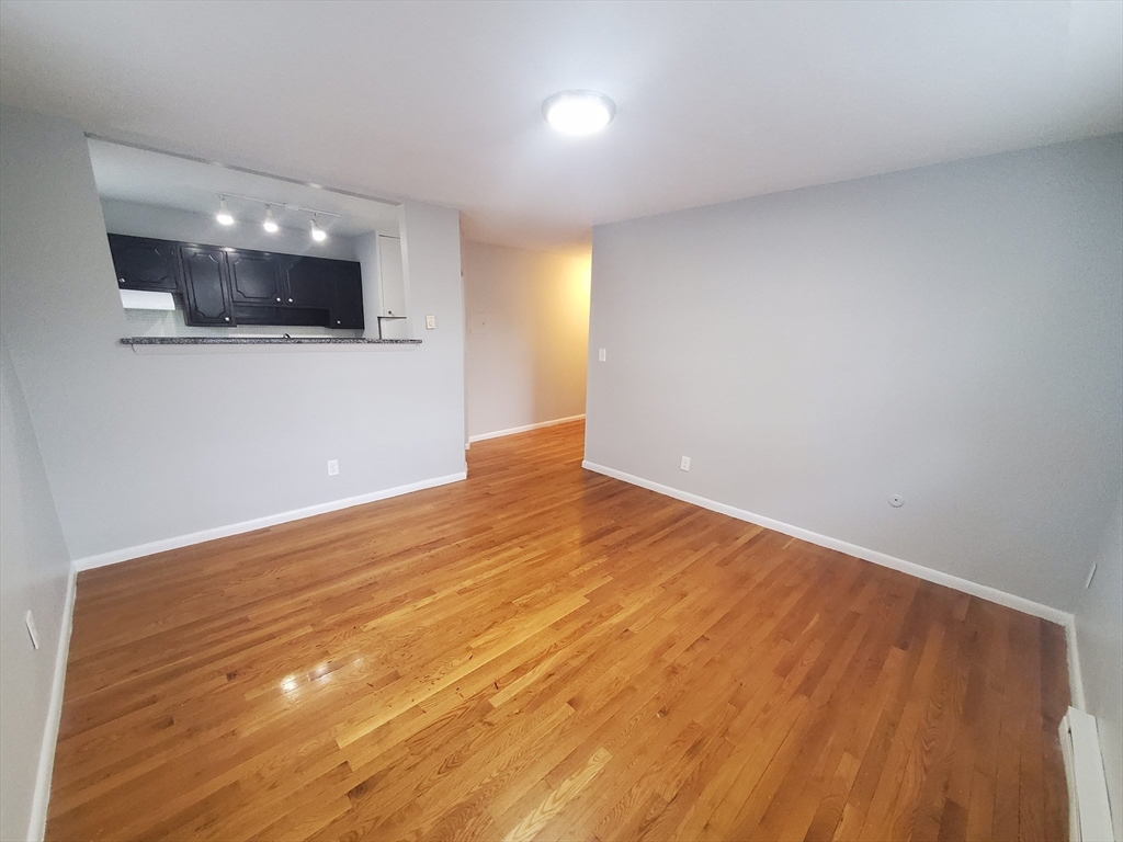 24 Colgate Road, Unit 5 Boston, MA 02131 - Photo 3 of 13 a view of an empty room with wooden floor and kitchen space