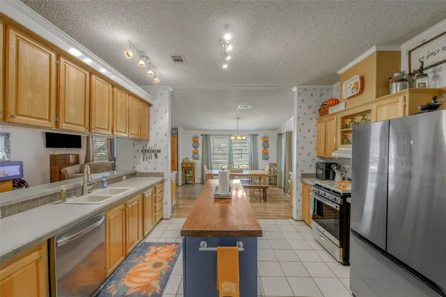 a kitchen with stainless steel appliances granite countertop a refrigerator a stove and a sink with cabinets