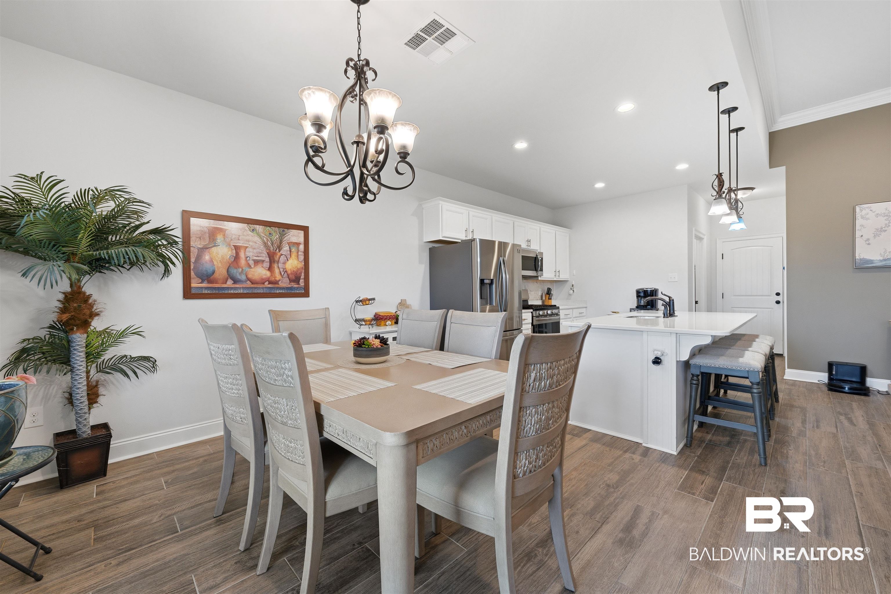 Dining space featuring suspended lighting, dark wood-style floors, and ornamental molding