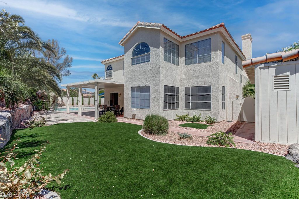 1 Rising Sun Court Henderson, NV 89074 - Photo 38 of 47 An inviting exterior with a well-maintained lawn and shaded patio area promises comfortable outdoor living.
