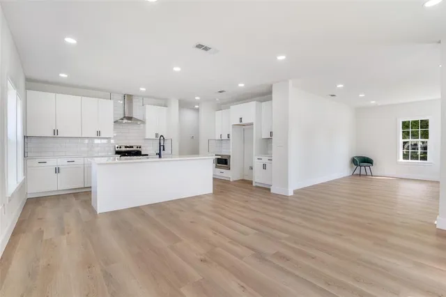 a view of kitchen with kitchen island a sink wooden floor and a stove top oven