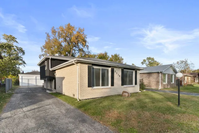 a view of a white house with a big yard and large tree