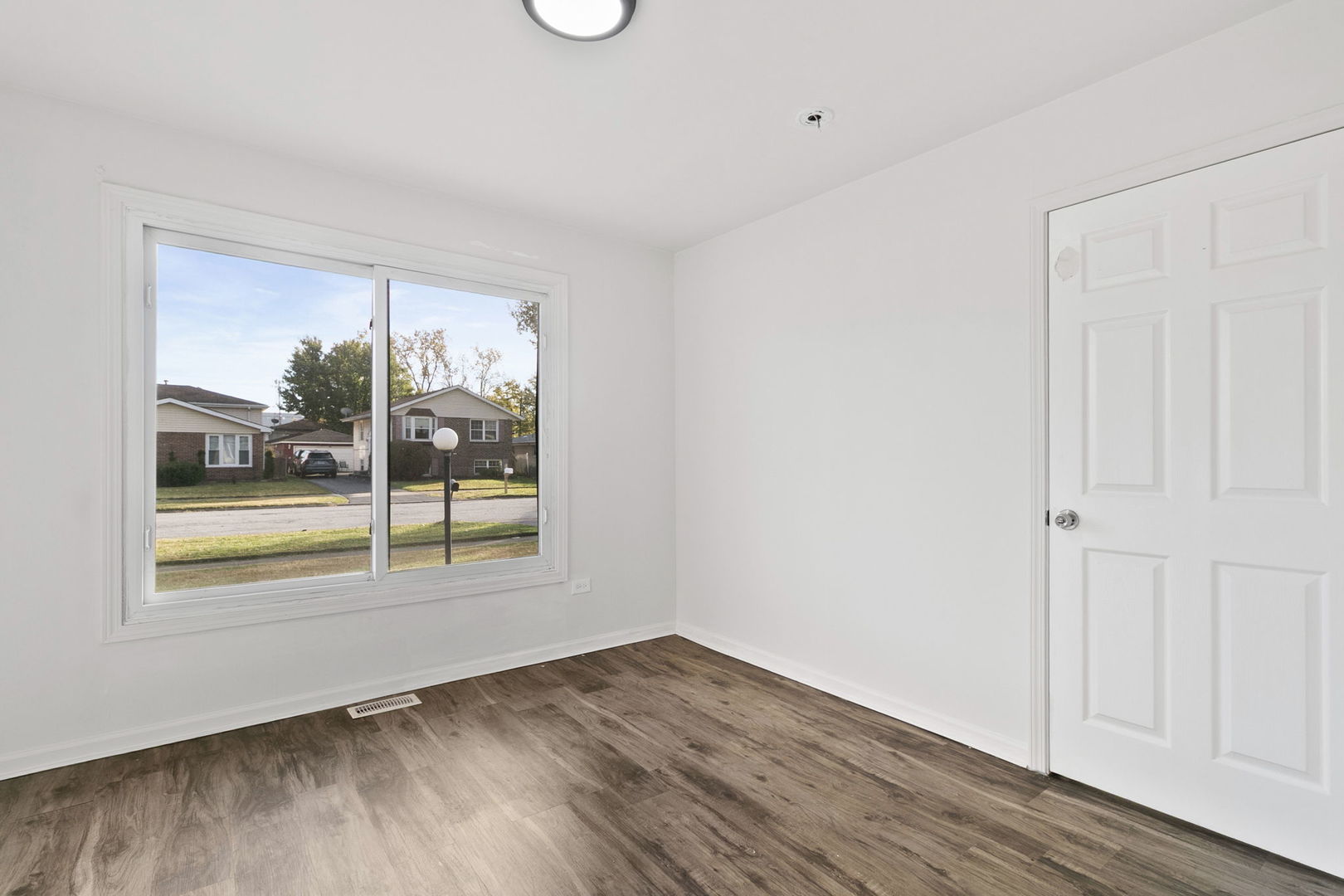 2236 West 157th Place Markham, IL 60426 - Photo 3 of 14 a view of an empty room with wooden floor and a window