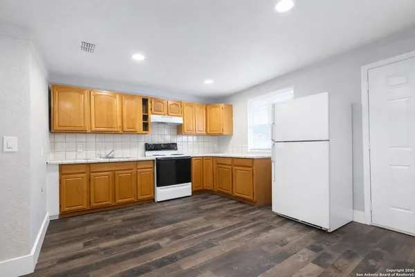 a kitchen with granite countertop wooden floors stainless steel appliances and a window