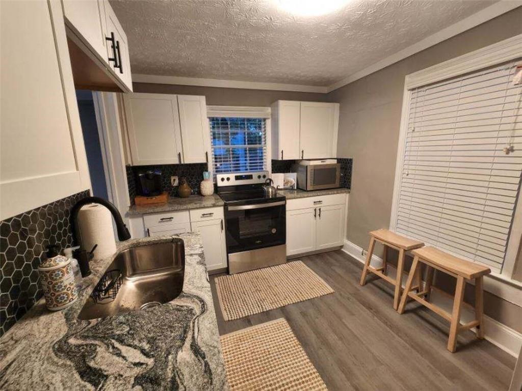 455 Lynch Avenue Northwest Atlanta, GA 30318 - Photo 6 of 11 a kitchen with a stove a sink dishwasher a dining table and chair with wooden floor