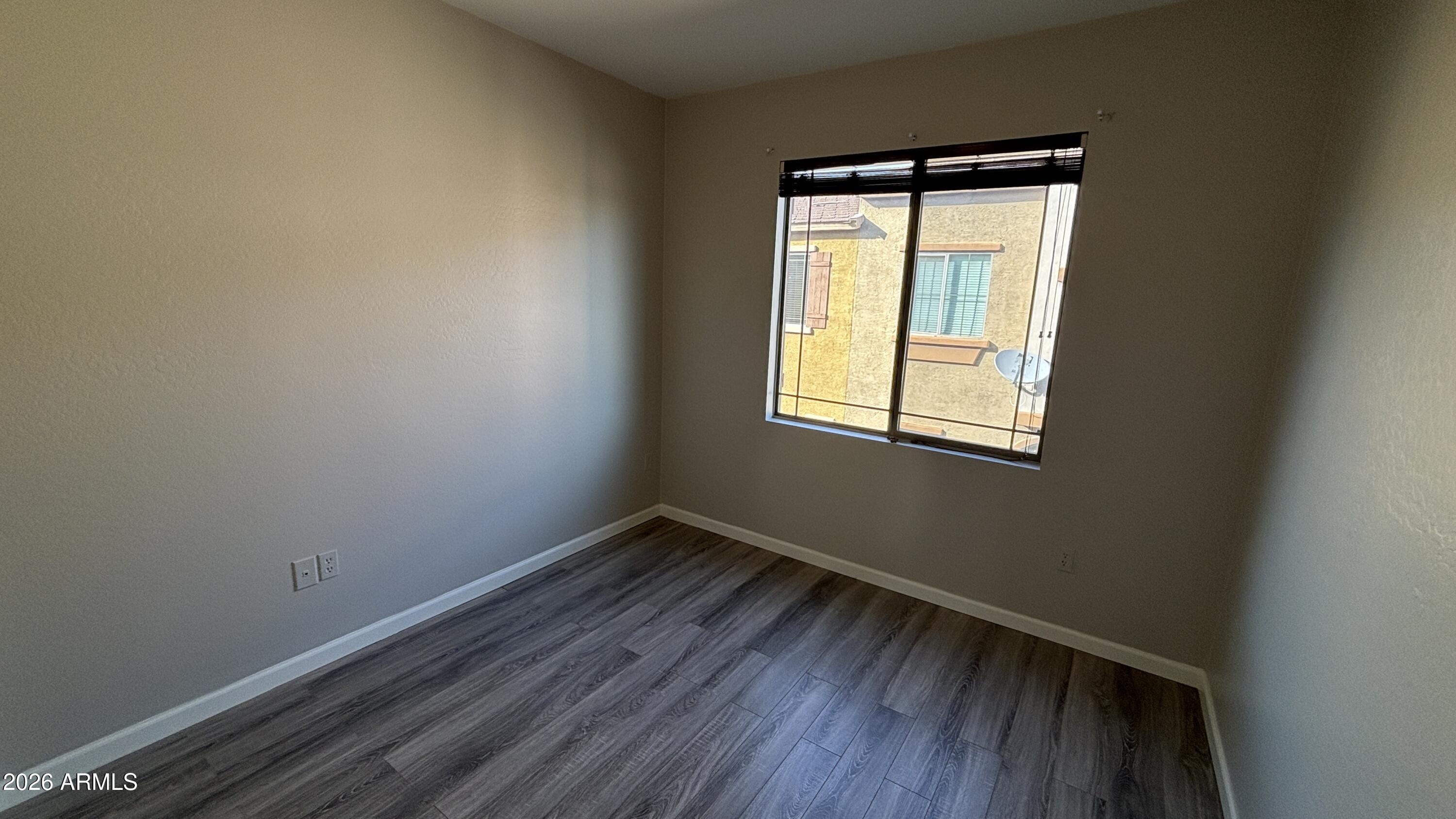 3250 West Greenway Road, Unit 104 Phoenix, AZ 85053 - Photo 20 of 26 a view of an empty room with wooden floor and a window