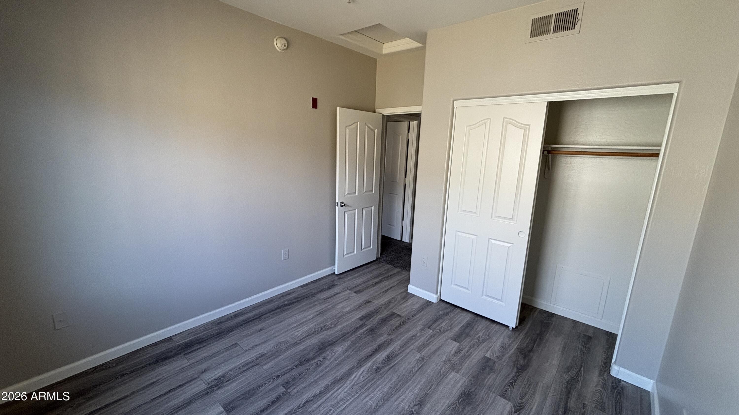 3250 West Greenway Road, Unit 104 Phoenix, AZ 85053 - Photo 21 of 26 a view of an empty room with wooden floor and a bathroom