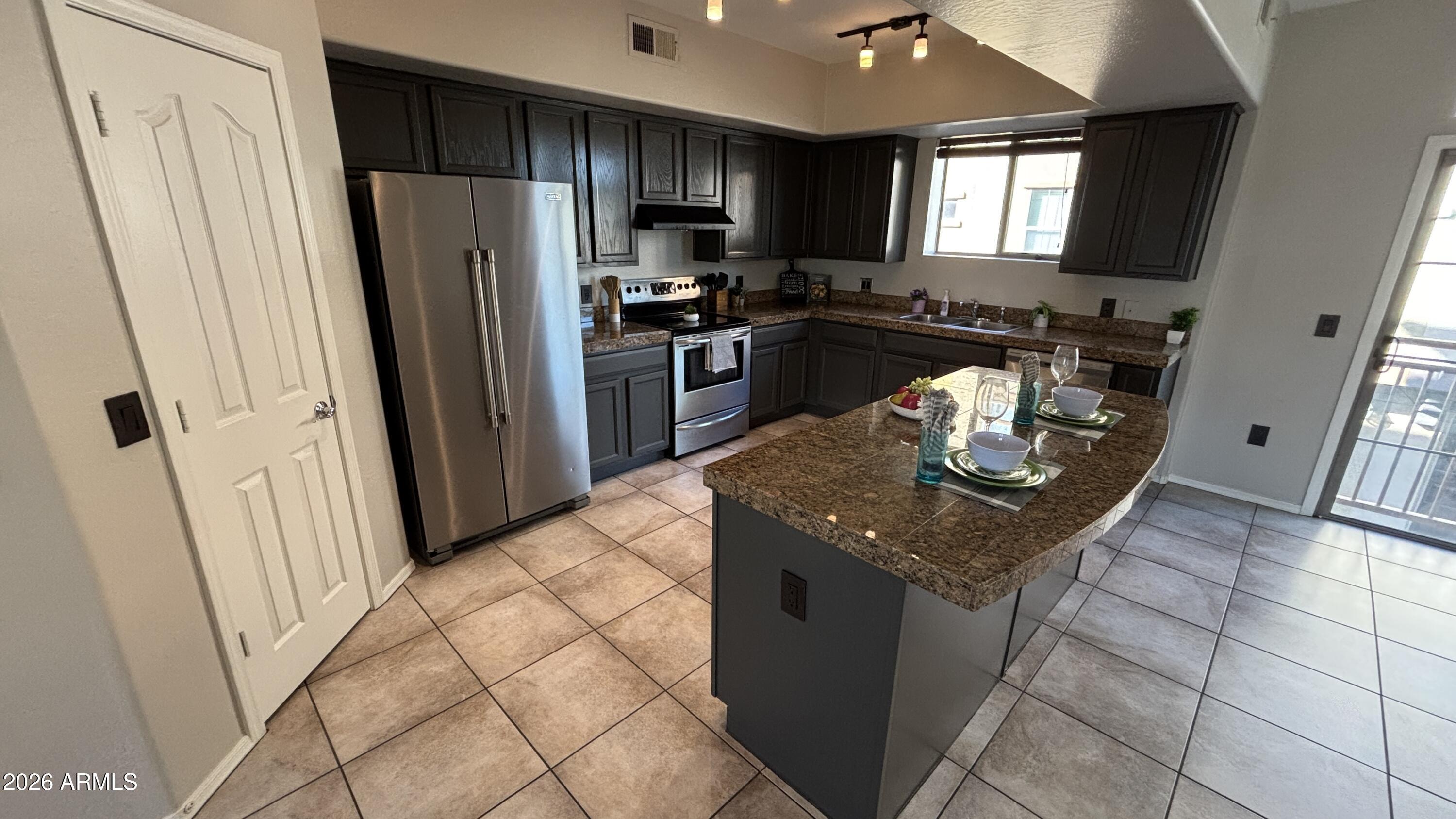 3250 West Greenway Road, Unit 104 Phoenix, AZ 85053 - Photo 9 of 26 a kitchen with stainless steel appliances granite countertop a refrigerator a stove a sink and a microwave