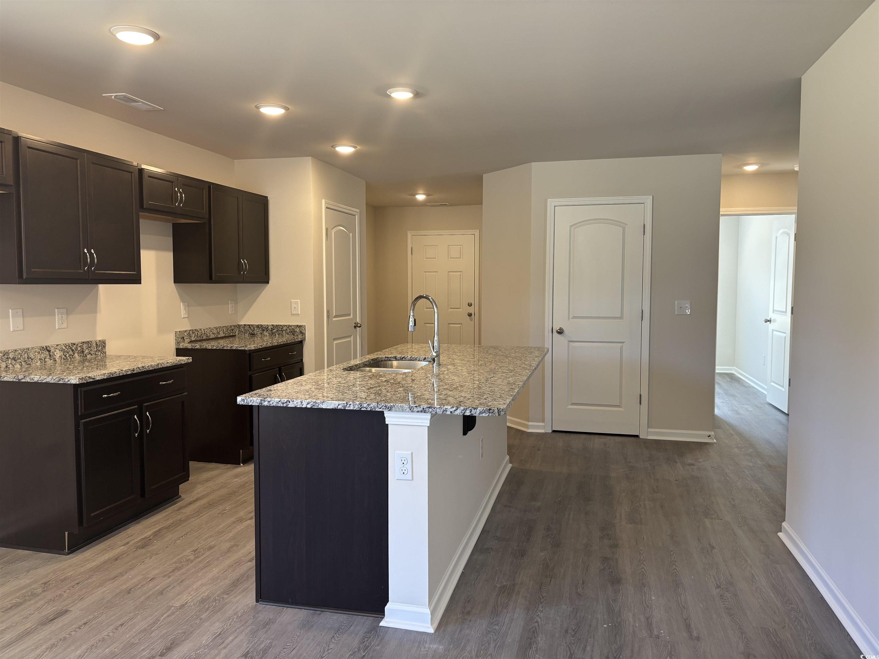 5725 Highway 41 Marion, SC 29571 - Photo 2 of 7 Kitchen featuring light stone counters, wood finished floors, recessed lighting, a center island with sink, and a breakfast bar
