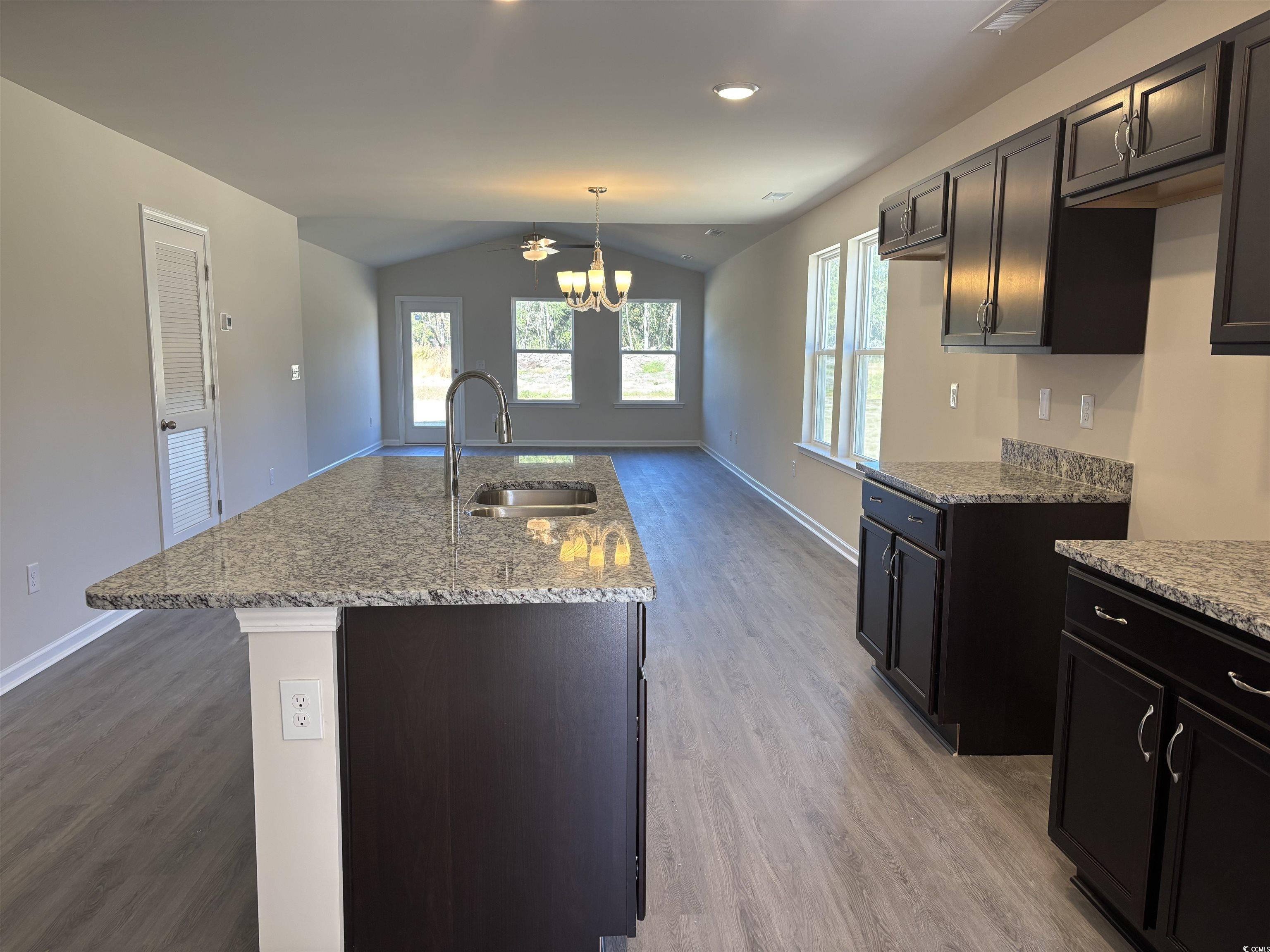 5725 Highway 41 Marion, SC 29571 - Photo 3 of 7 Kitchen with lofted ceiling, light wood-style floors, light stone countertops, decorative light fixtures, and a kitchen island with sink