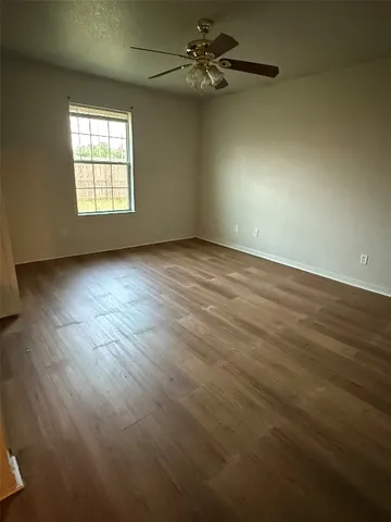 an empty room with wooden floor ceiling fan and windows